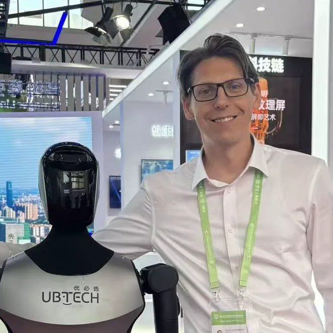 Nicolas Anders von der Werbeagentur WOLQE mit einem humanoiden Roboter auf einer Technologiemesse